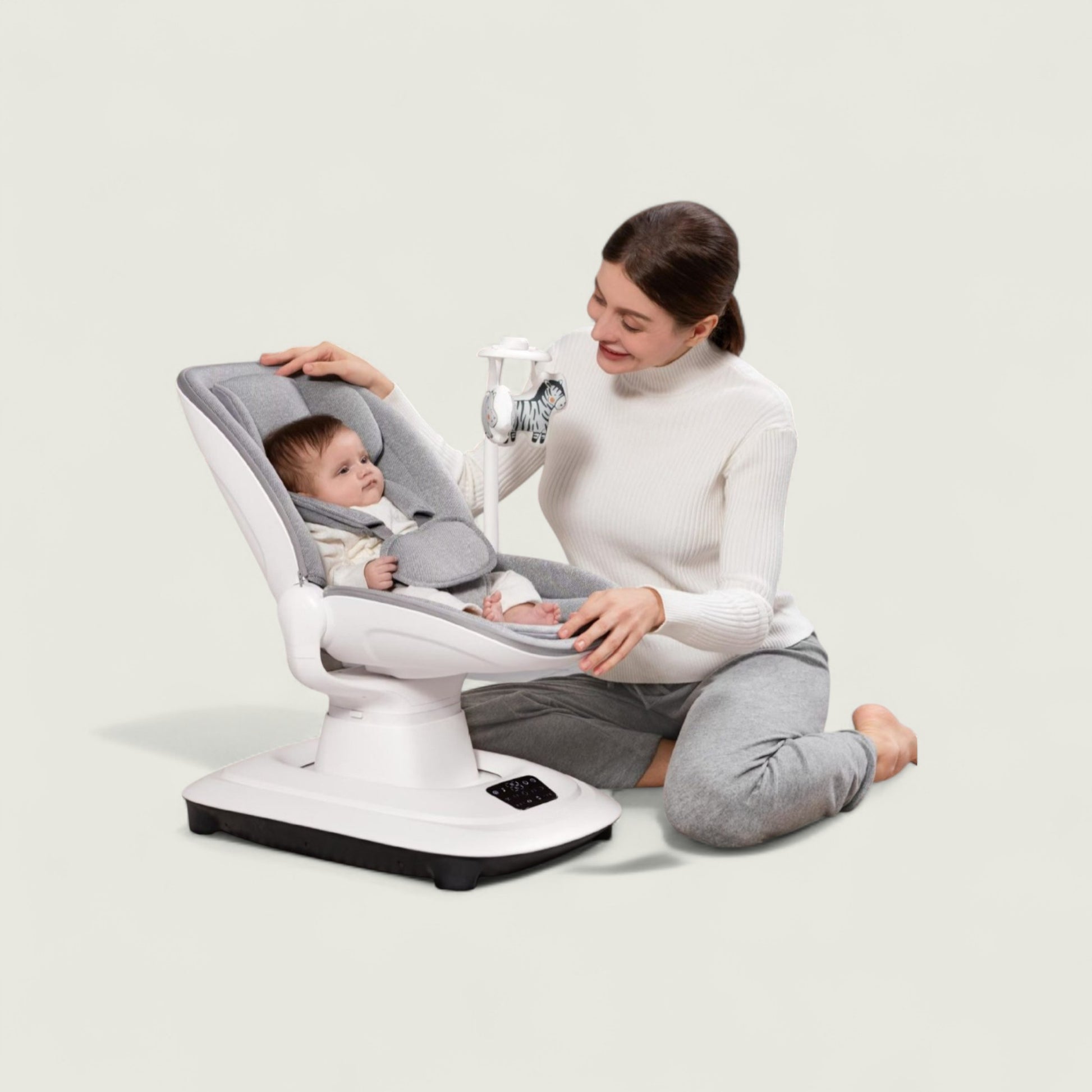 Woman sitting with a baby in a modern baby seat on a plain background