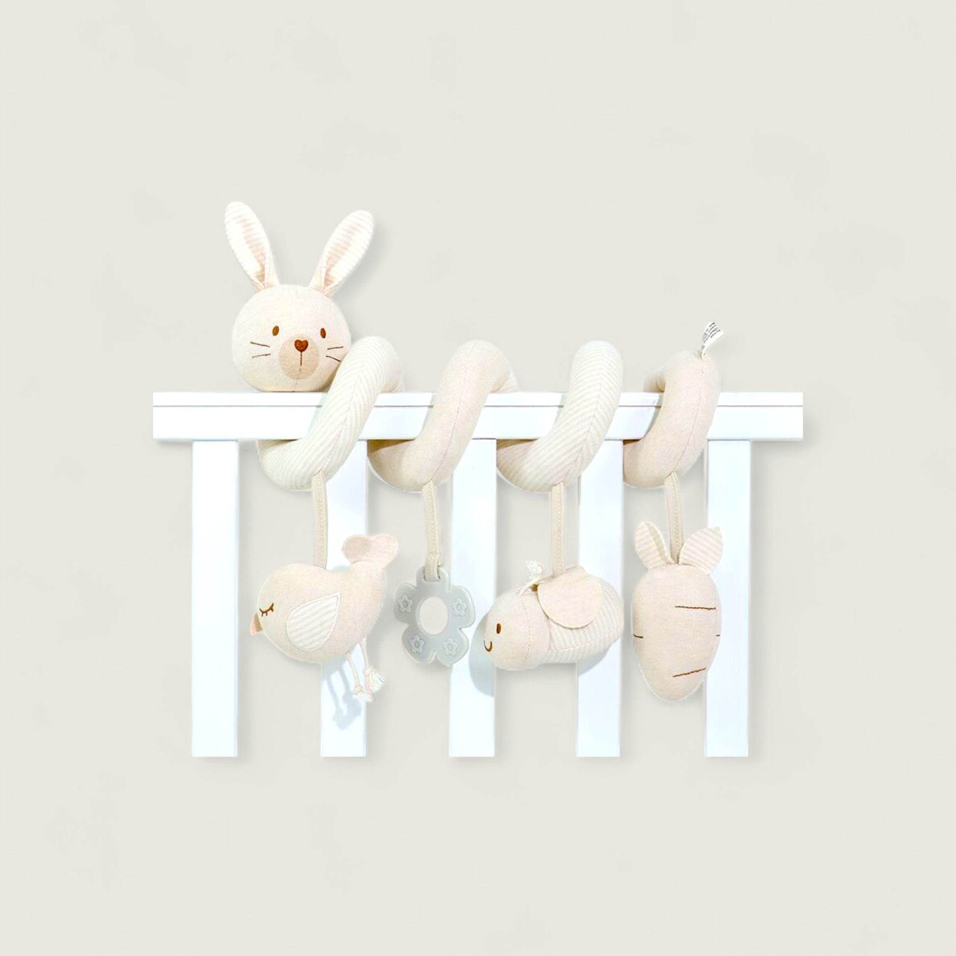 Set of plush toys hanging from a white rod against a light gray background