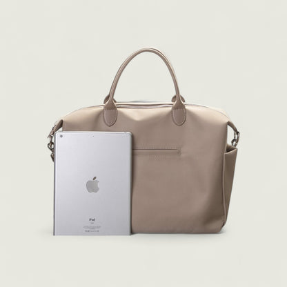 Beige handbag with an Apple iPad inside on a light gray background