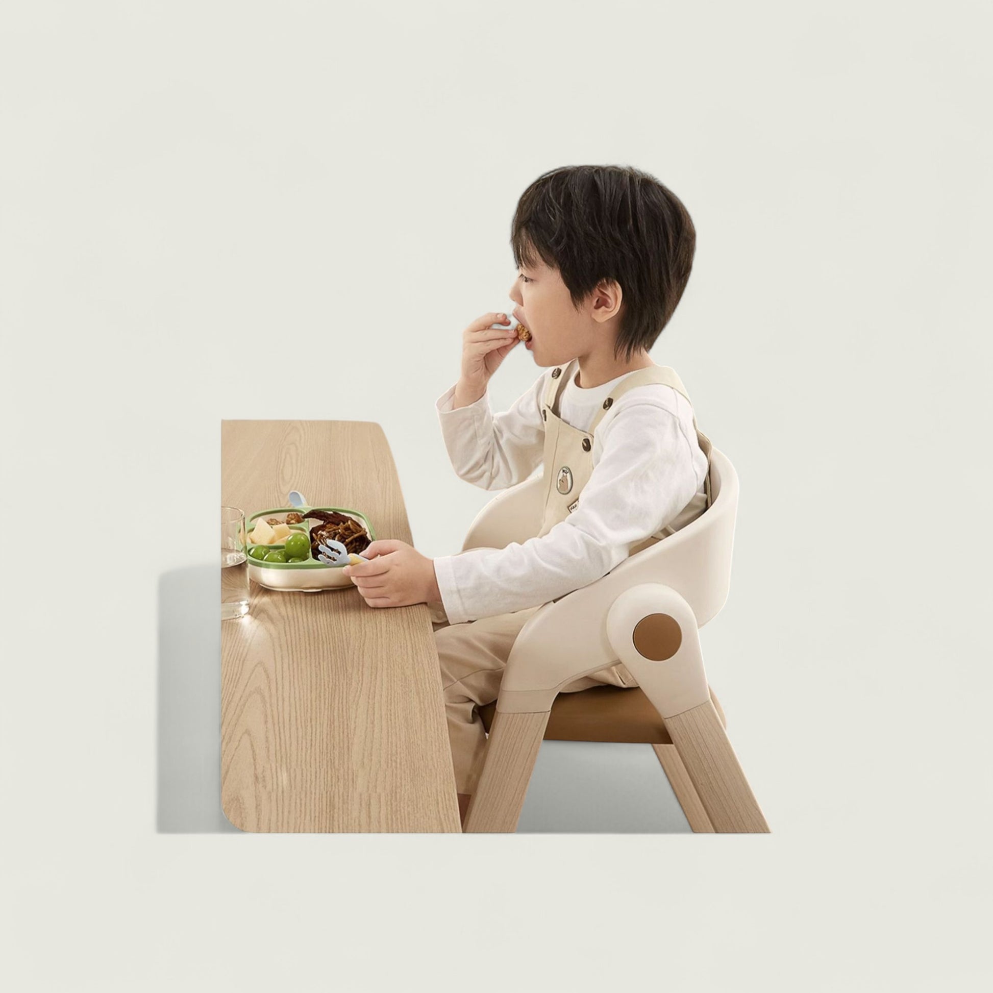 Child sitting at a small wooden table eating with a chair that has a unique design.