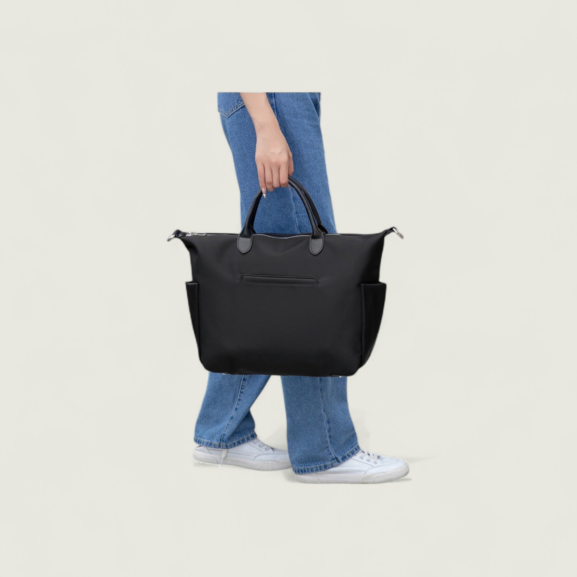 Person holding a black handbag against a plain background