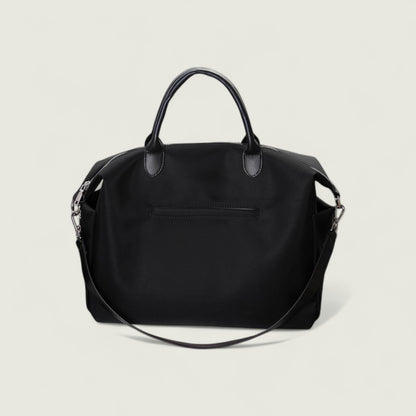 Black handbag with a shoulder strap on a light beige background