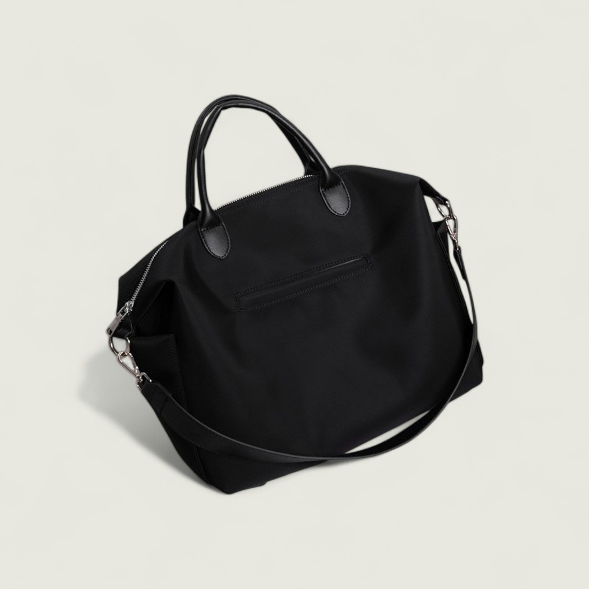 Black handbag with a shoulder strap on a light gray background