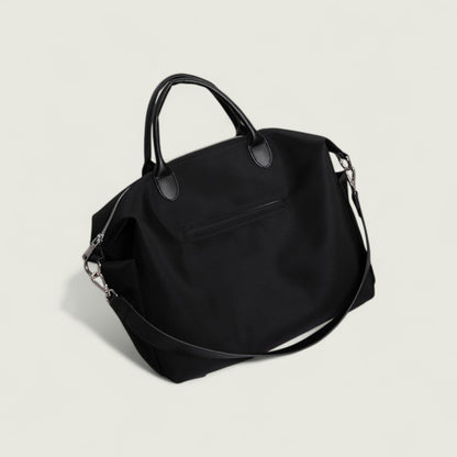 Black handbag with a shoulder strap on a light gray background