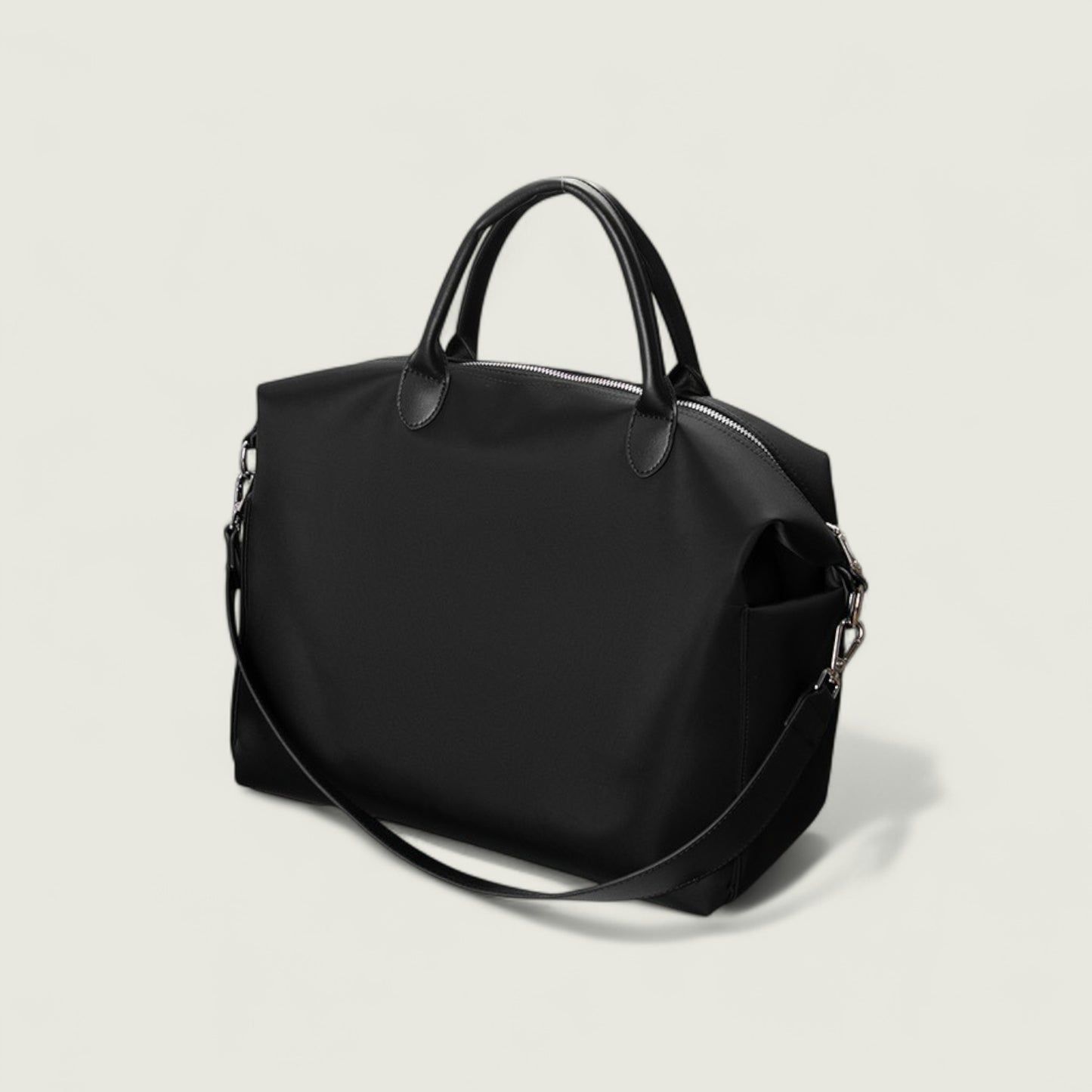 Black handbag with a shoulder strap on a light gray background