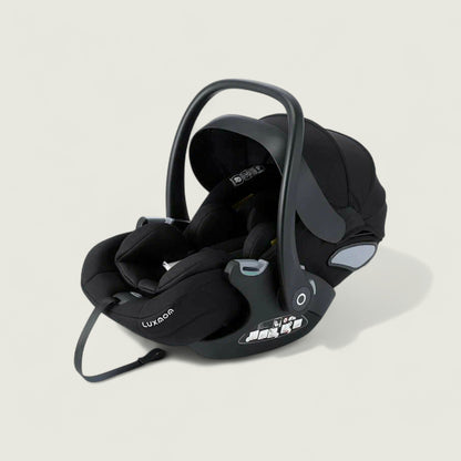 Black baby car seat with visible branding on a light beige background