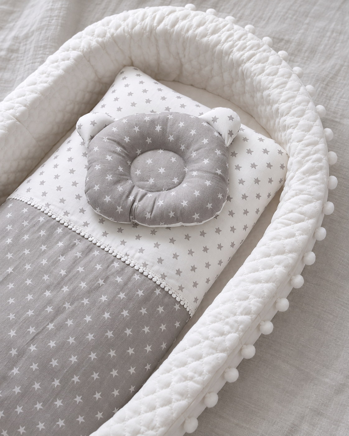 DreamNest close-up showing white quilted edge, star-pattern pillow and matching blanket