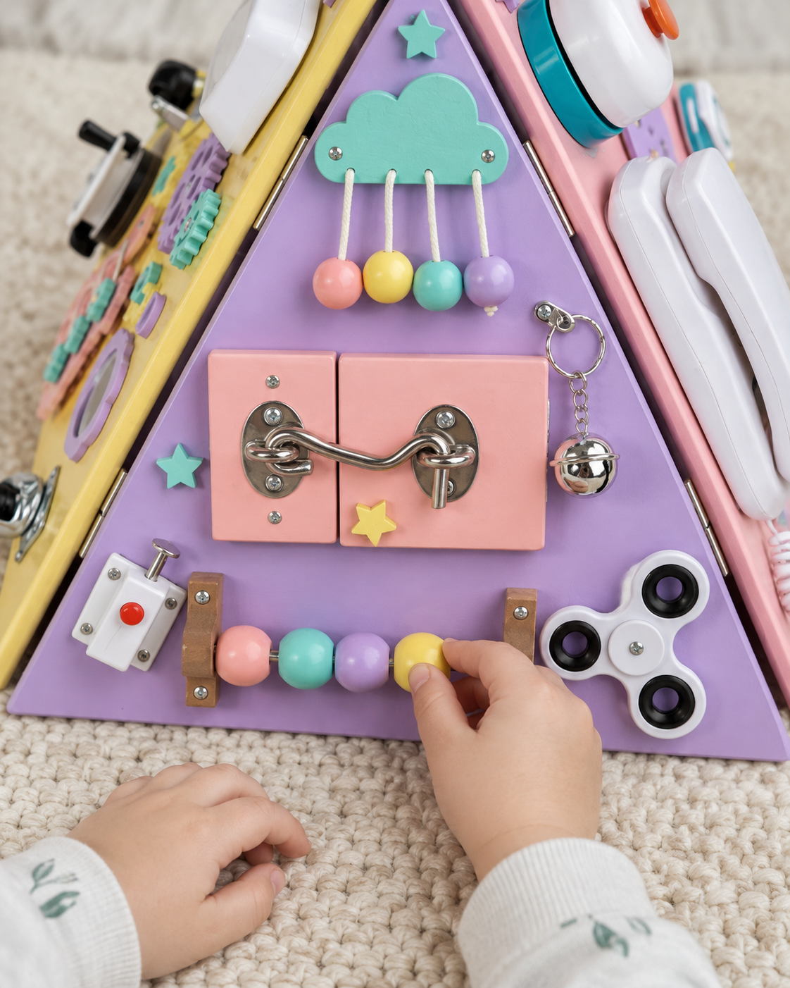 Child sliding a bead on the purple activity pyramid with latch, bell and spinner visible