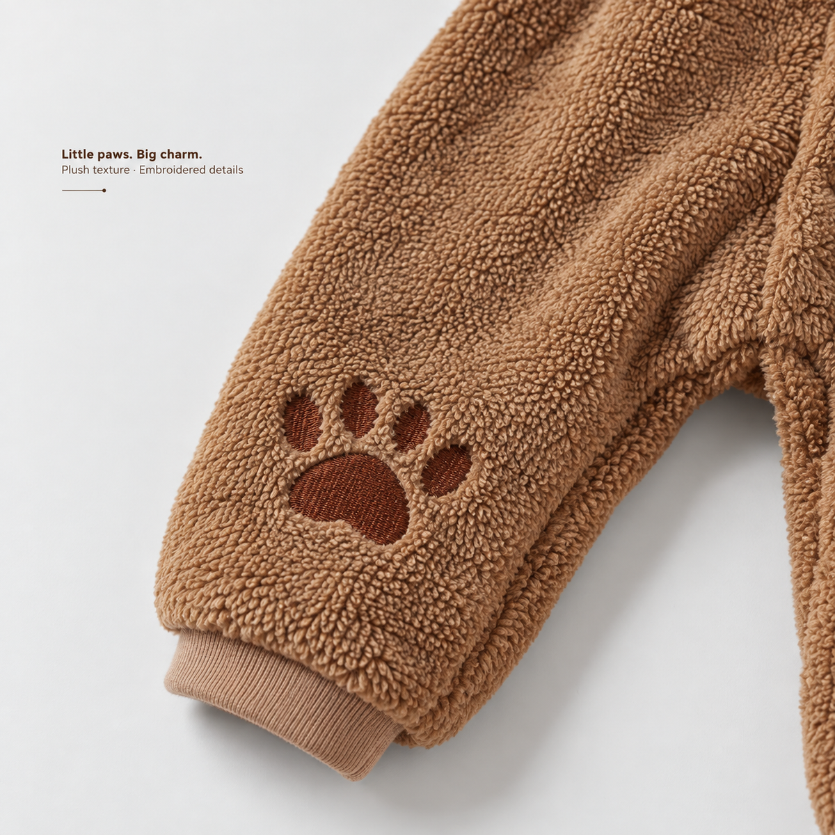 Bear Jumpsuit — brown plush texture, embroidered paw and ribbed ankle cuff.