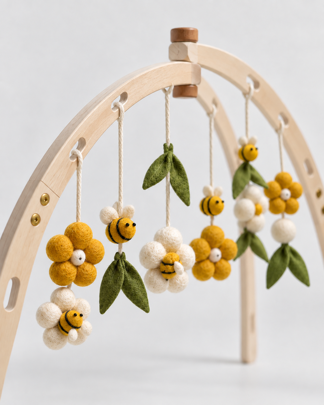 PerfectBaby felt bee and flower toys shown hanging from a curved wooden play arch