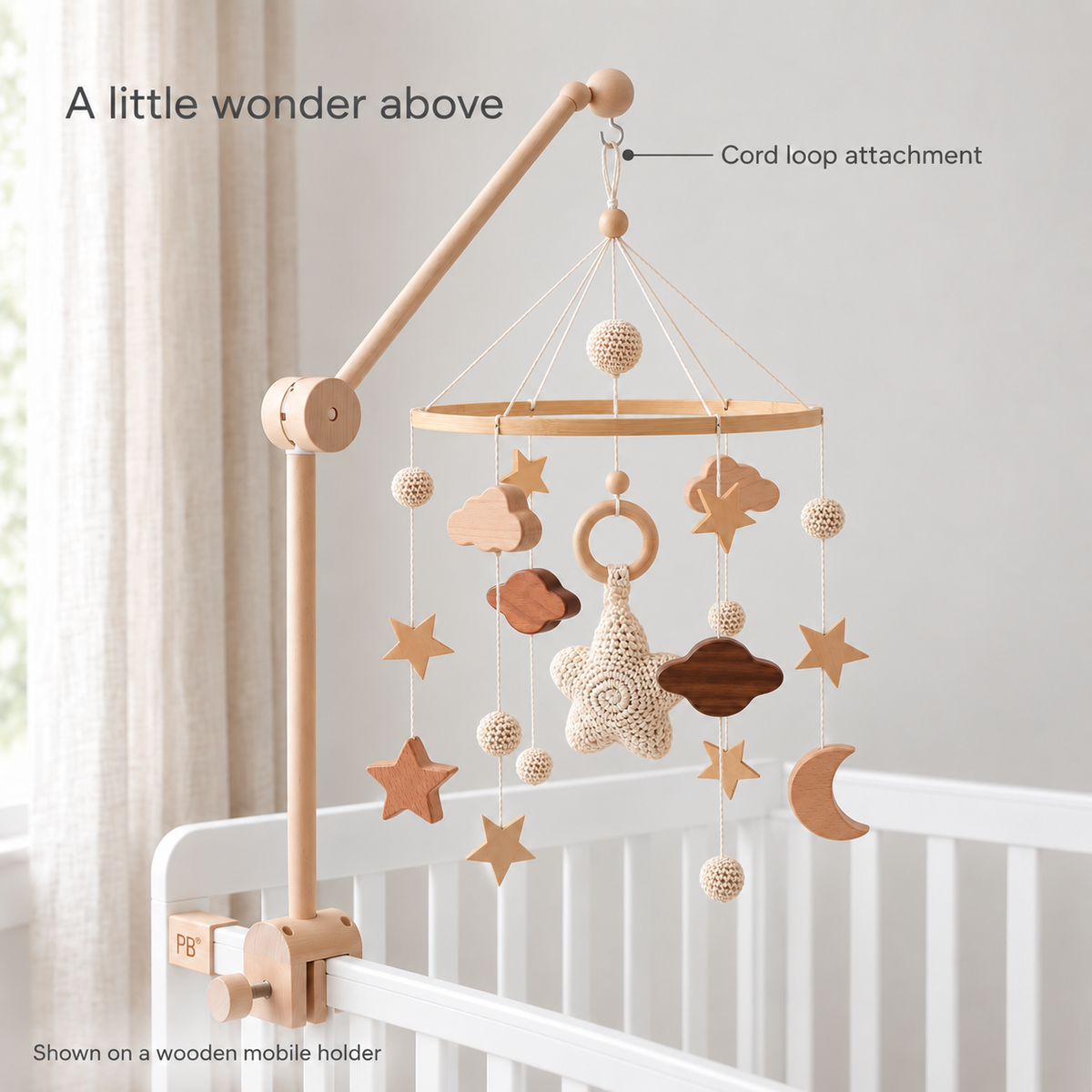 Moonveil beige mobile hanging by its cord loop on a wooden crib holder