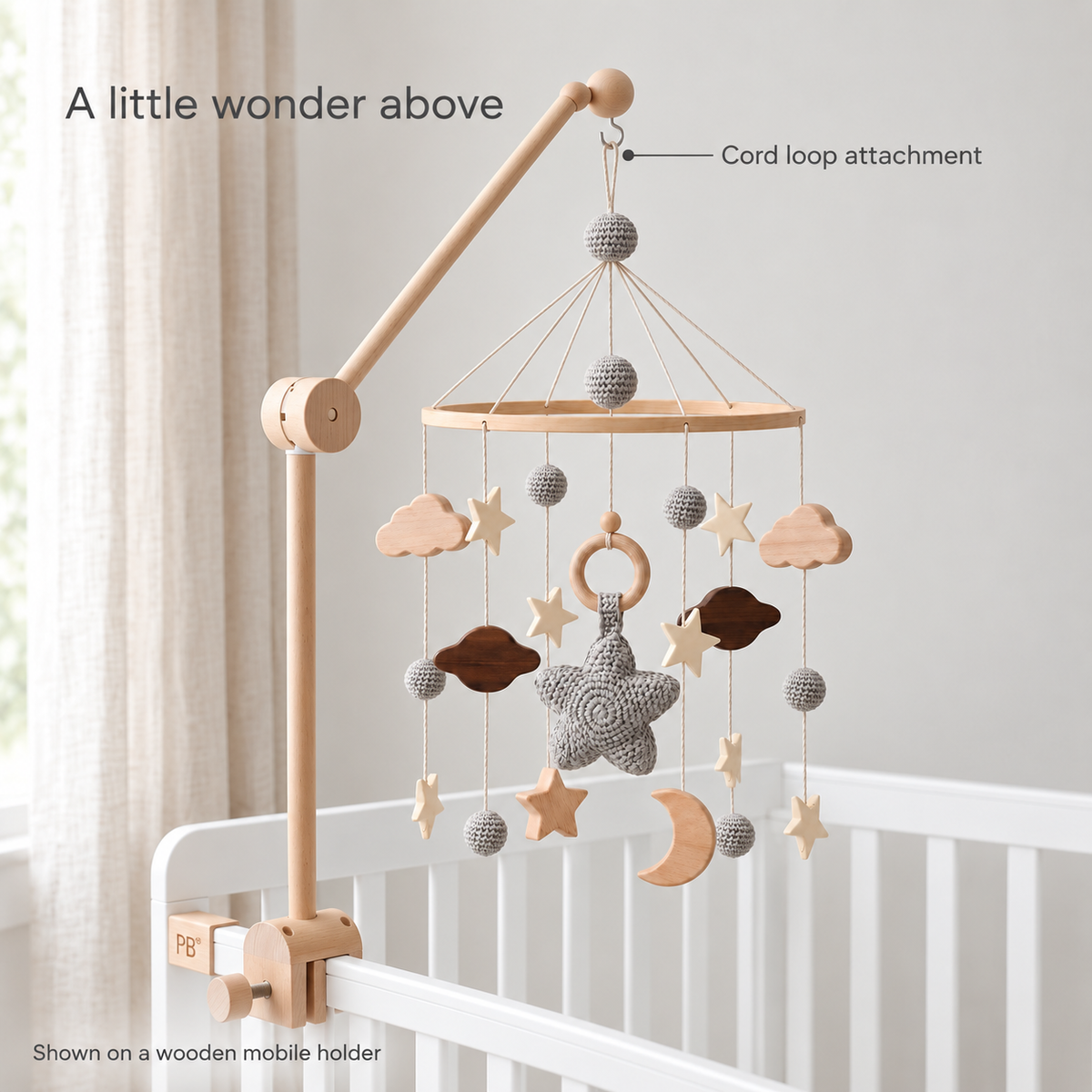 Moonveil grey mobile hanging by its cord loop on a wooden crib holder