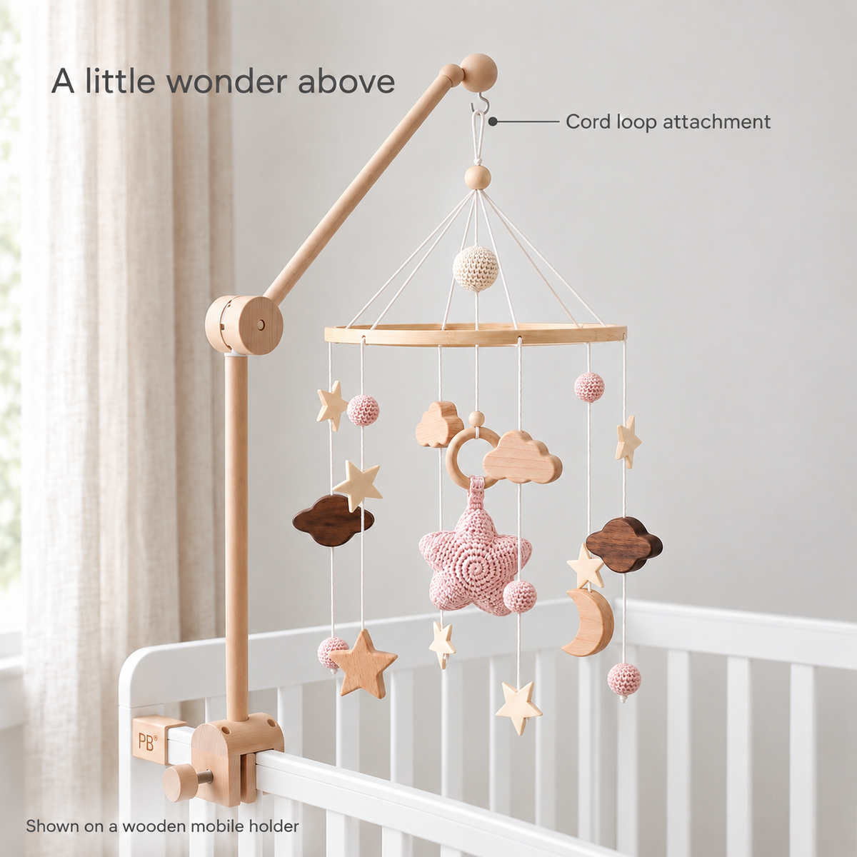 Moonveil pink mobile hanging by its cord loop on a wooden crib holder