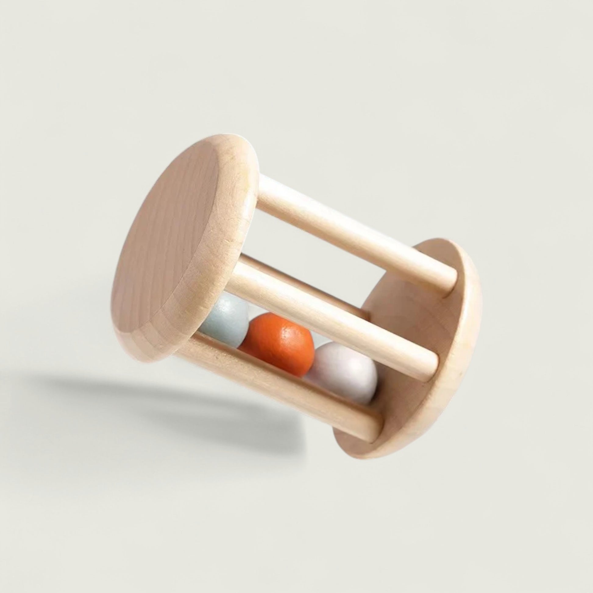 Wooden baby rattle with three colored beads on a light gray background