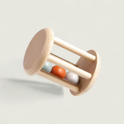 Wooden baby rattle with three colored beads on a light gray background