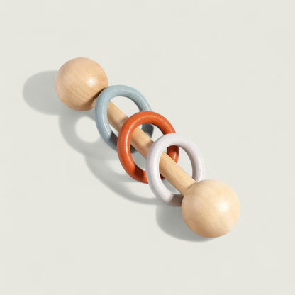 Wooden baby teething ring with colorful rings on a light background