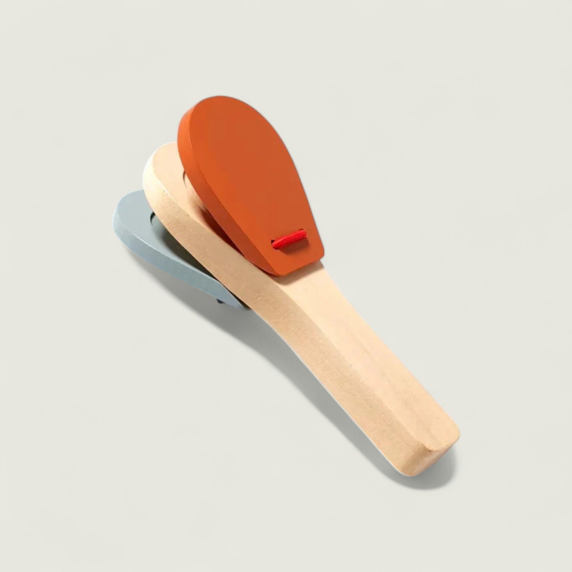 Two wooden paddles with orange and beige tops on a light gray background