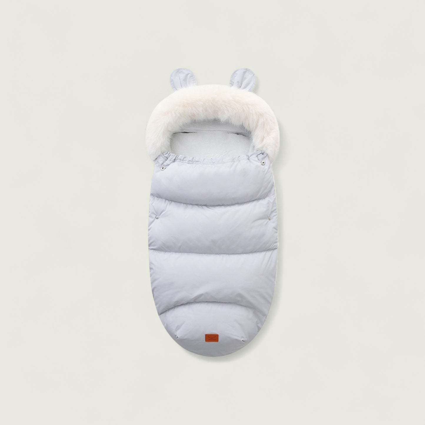 Light gray baby sleeping bag with white fur trim on a beige background