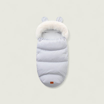 Light gray baby sleeping bag with white fur trim on a beige background