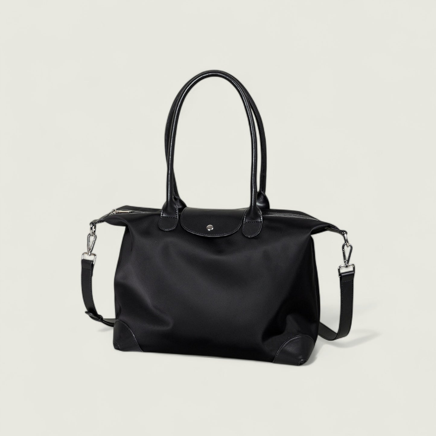 Black handbag with a shoulder strap on a light gray background