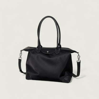 Black handbag with a shoulder strap on a light gray background