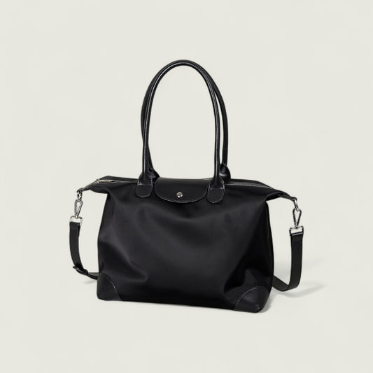Black handbag with a shoulder strap on a light gray background