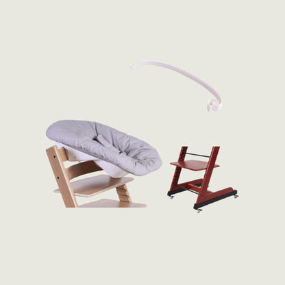 Wooden baby swing with gray cushion and red high chair on a beige background