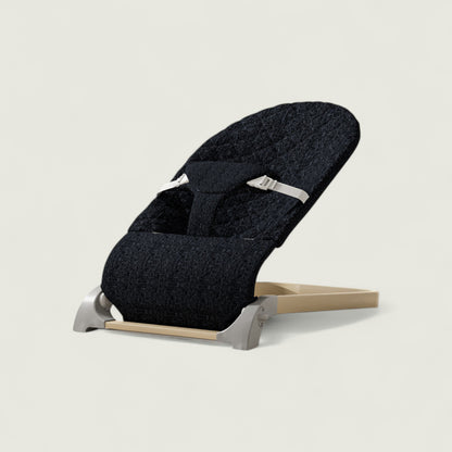 Black baby seat with beige base on a light gray background