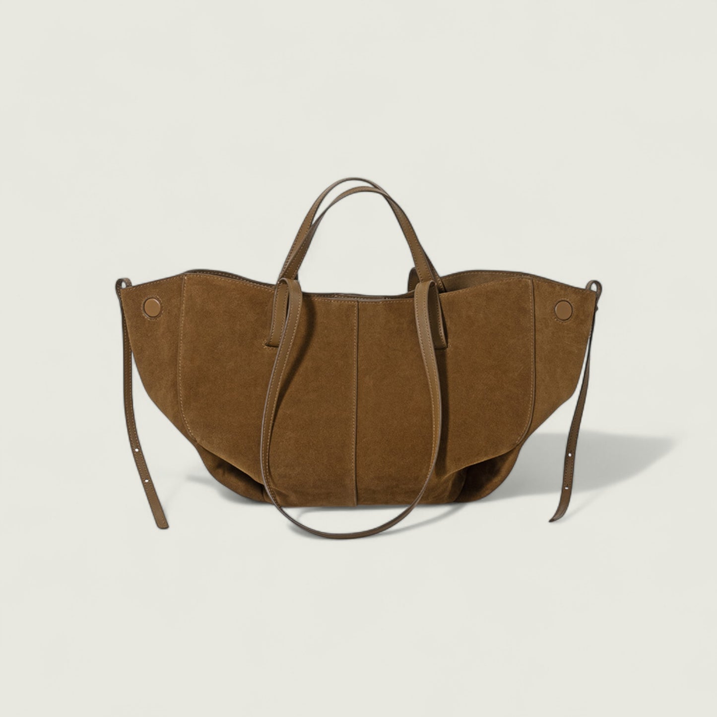 Brown suede handbag with shoulder strap on a light beige background