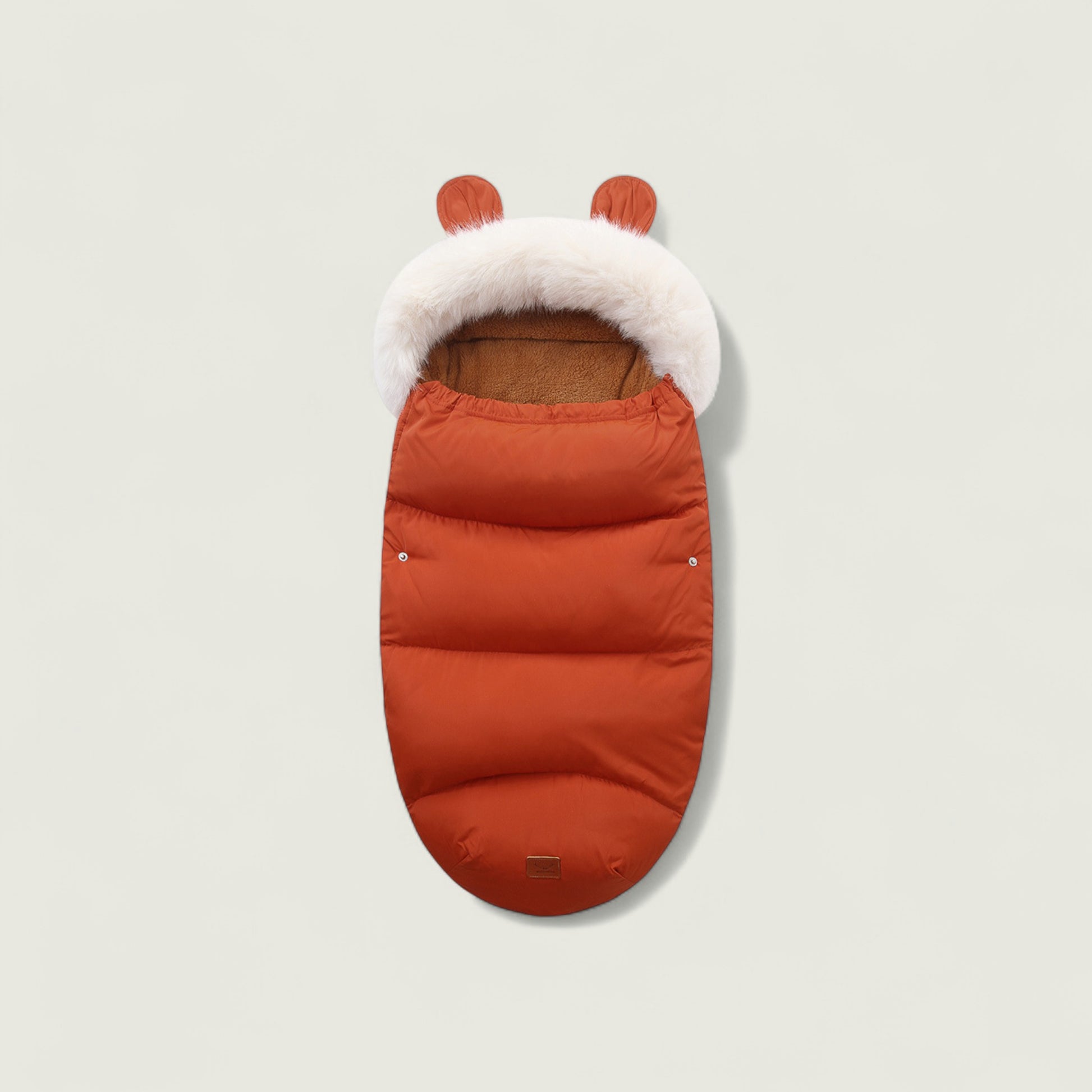 Orange baby footmuff with white fur lining and brown interior on a light gray background